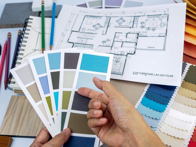 Hand holding paint swatches with floor plan, fabrics