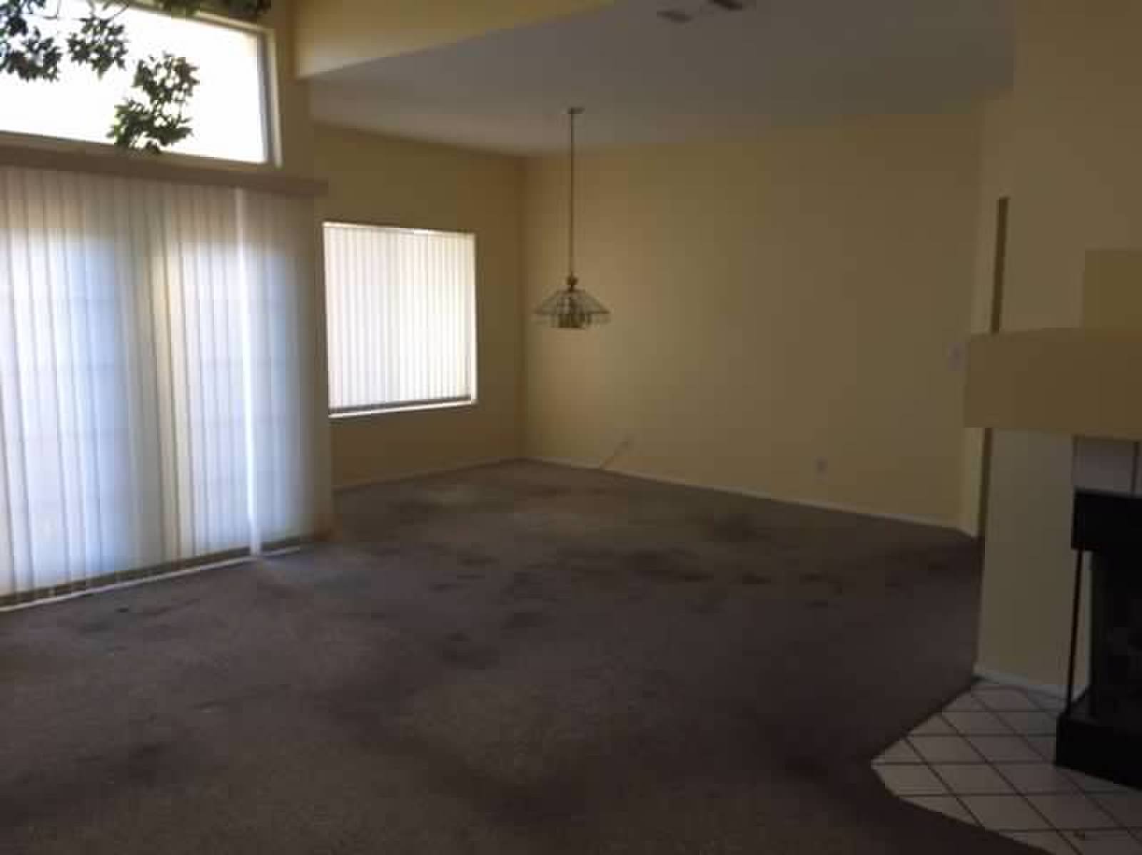 Empty living room with carpet, fireplace, vertical blinds