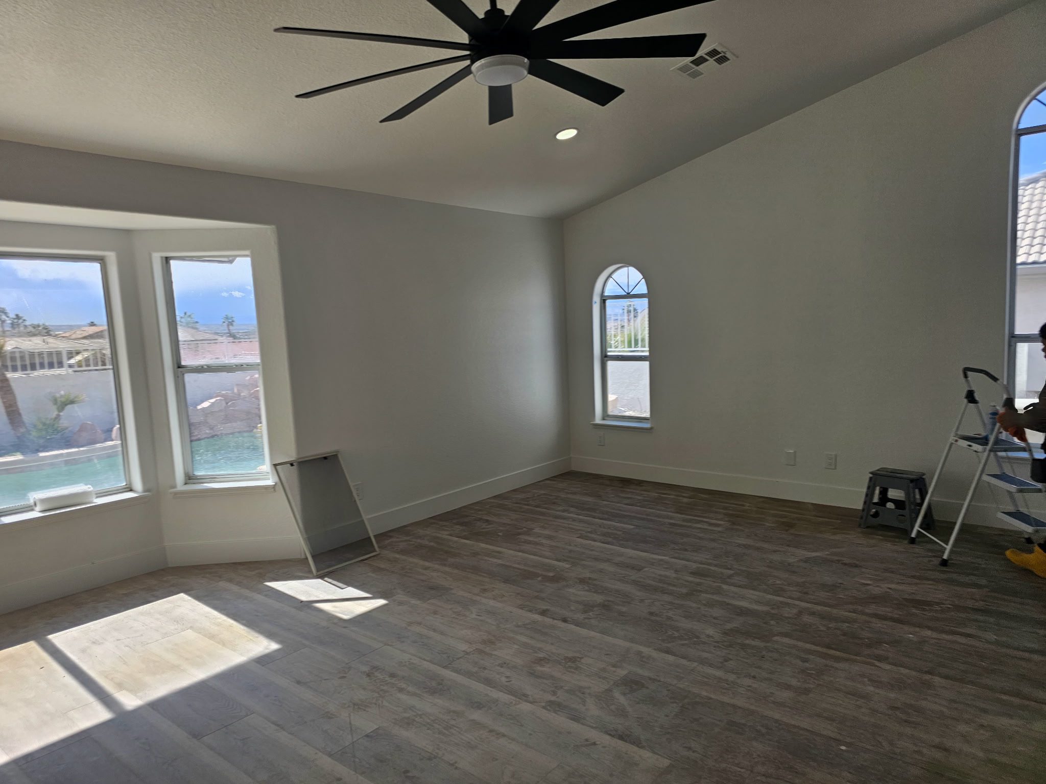 Empty bright room with ceiling fan and windows