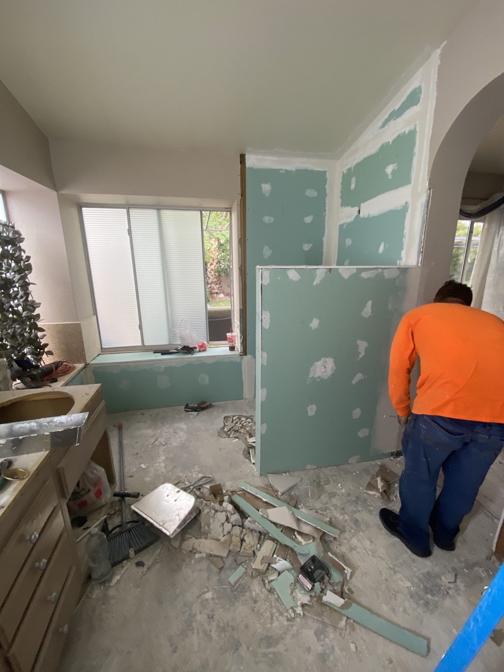 Worker installing drywall during bathroom renovation