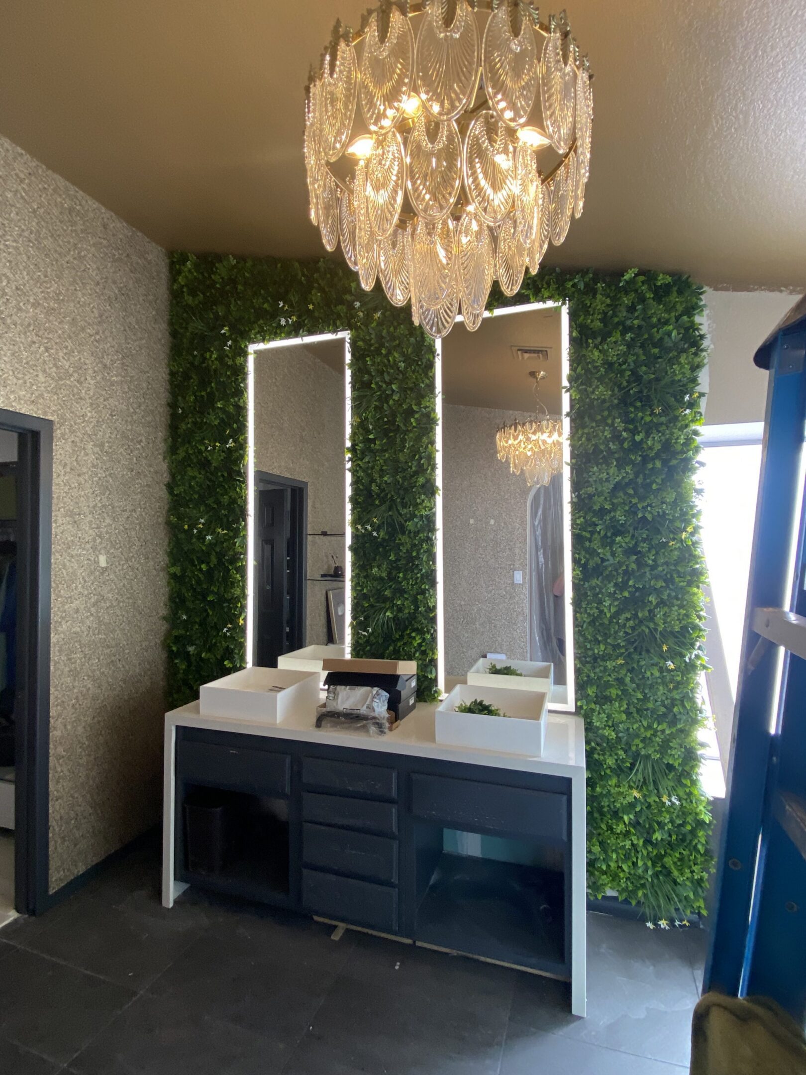 Vanity with green foliage wall and chandelier