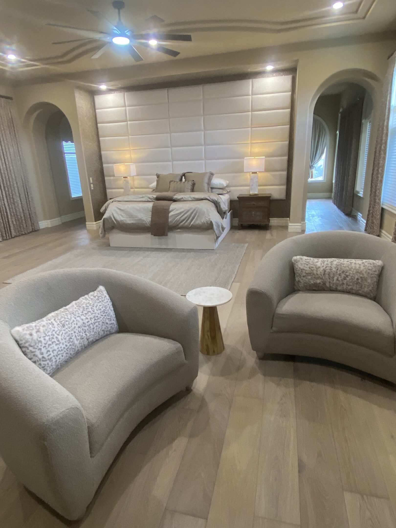 Neutral luxury master bedroom with curved armchairs