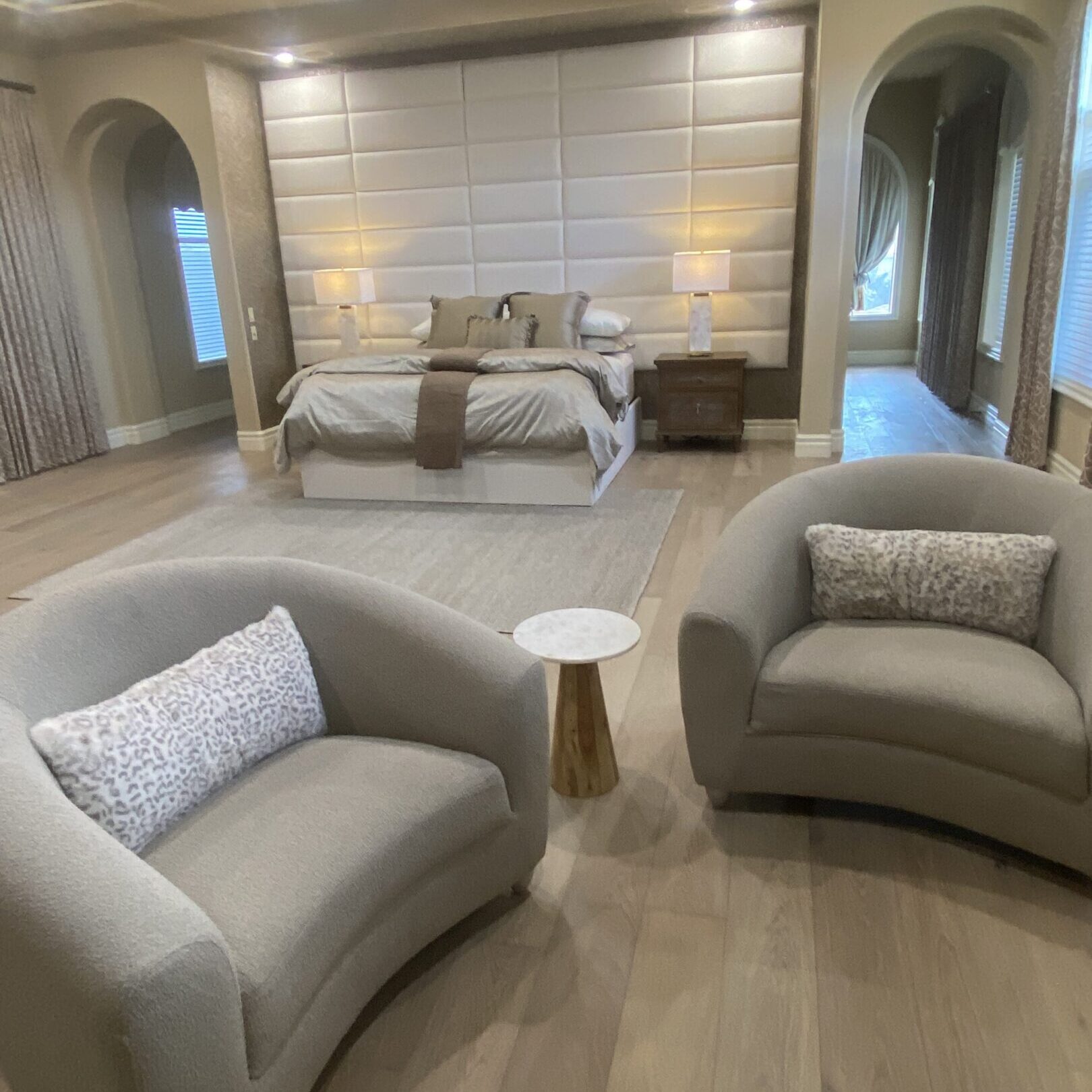 Neutral luxury master bedroom with curved armchairs